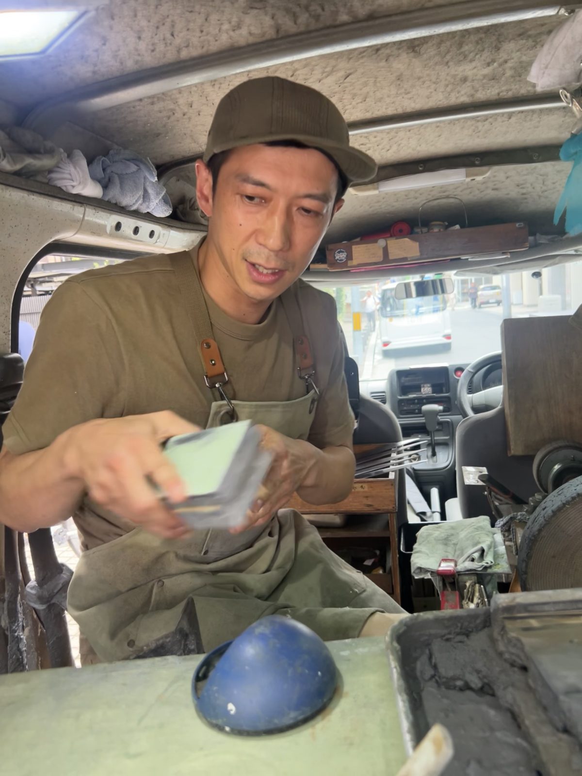 専用車の中で、砥石を手にこちらに話しかける金森俊樹さん