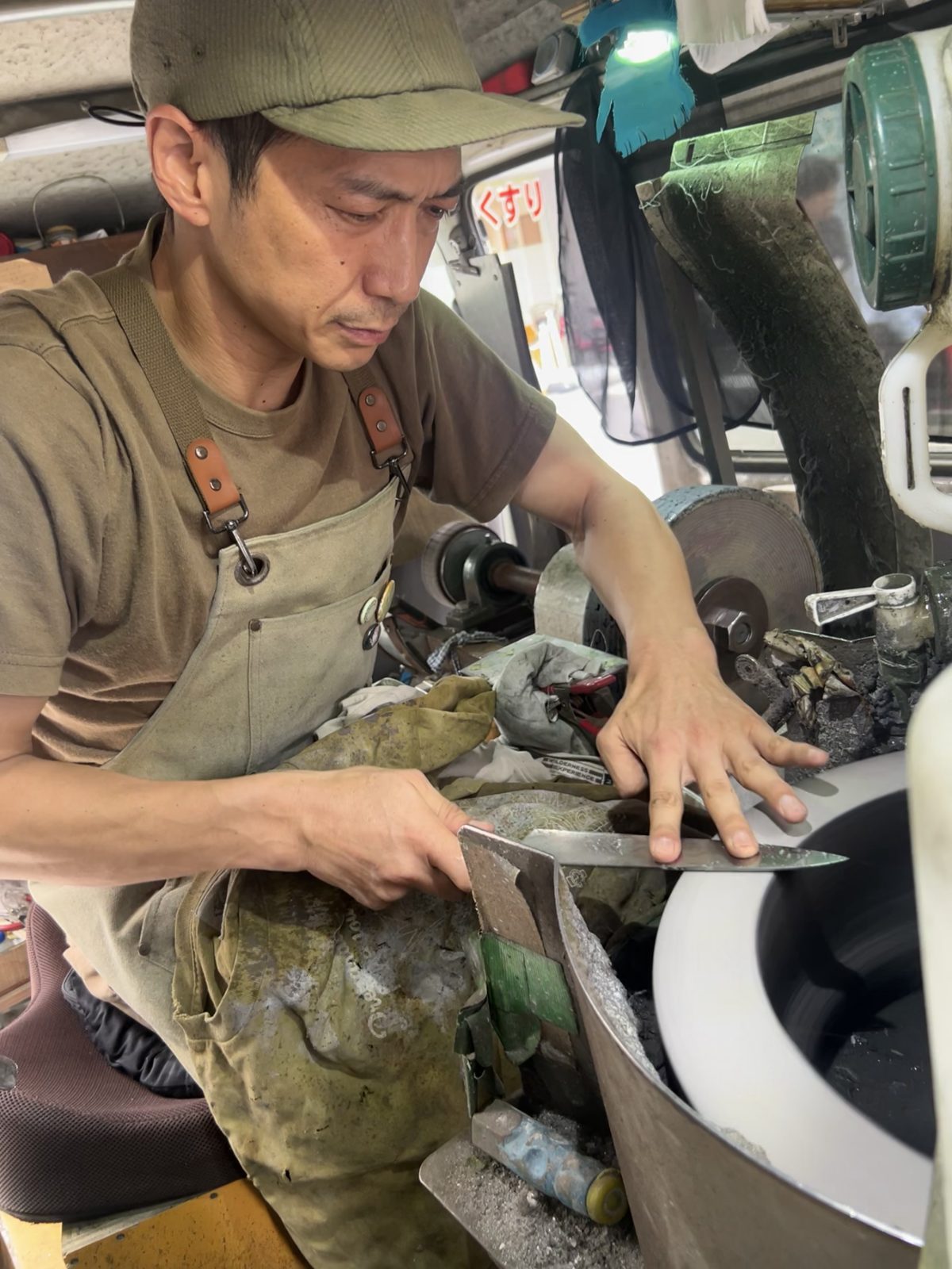 砥ぎ機で包丁を荒砥ぎする様子