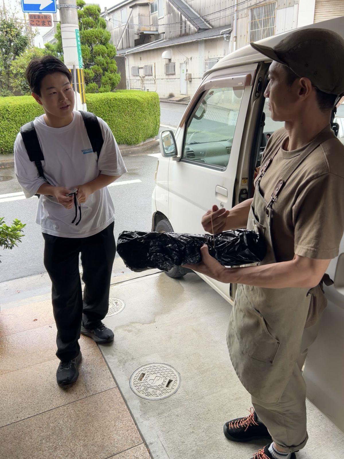 お店の前で、専用車のそばで刃物を受け渡す様子