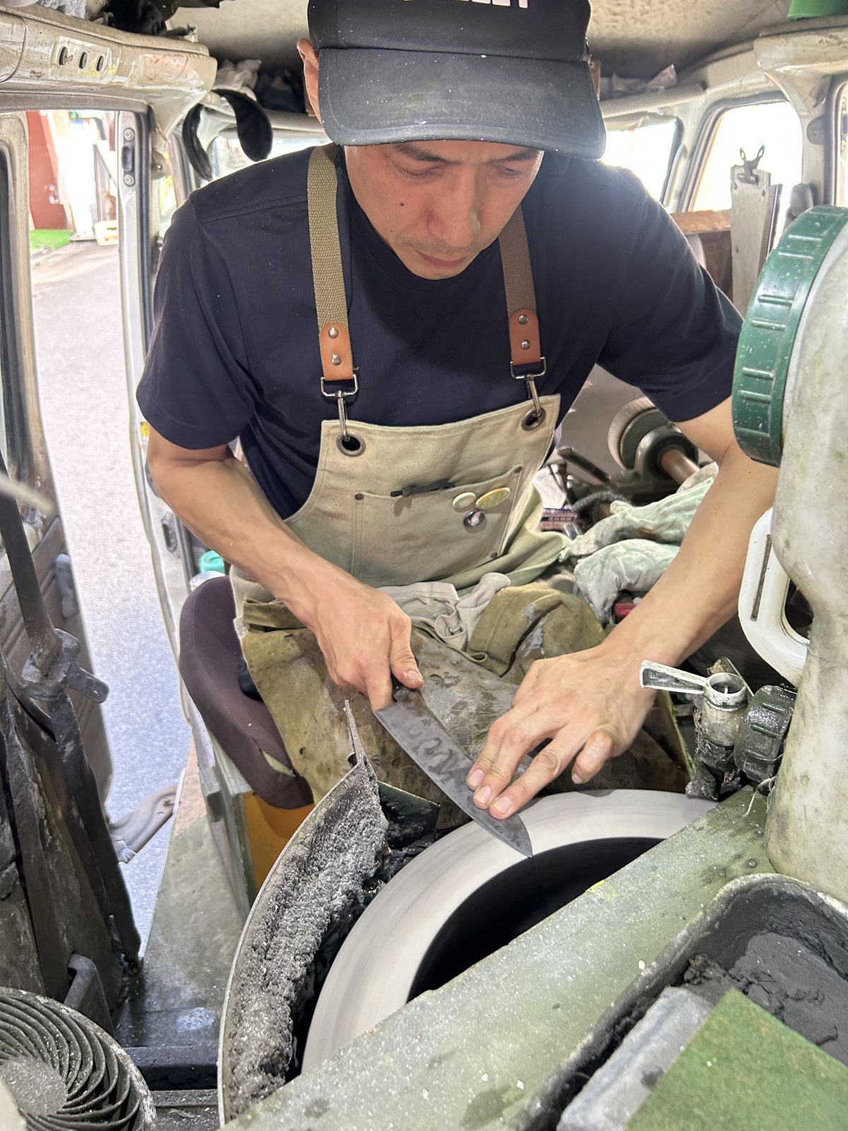 専用車の中で、砥石に刃物を当てる金森俊樹さん